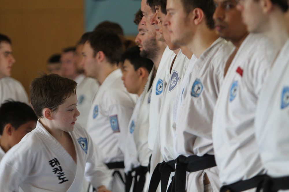 young boy inspects adult taekwondo competitors