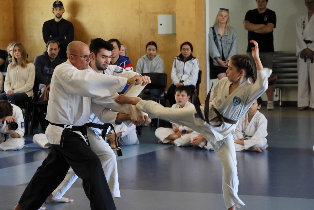 JUnior girl kicking wooden board at Taekwondo