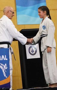 Taekwondo student being awarded Junior Black Beltfrom Grand Master