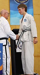 Taekwondo student receiving junior Black Belt from Grand Master